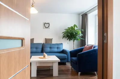 a living room with a blue couch and a table at G & M Apartamentai in Anykščiai