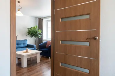 a door to a living room with a blue couch at G & M Apartamentai in Anykščiai