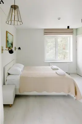 a white bedroom with two beds and a window at Green Town in Vievis