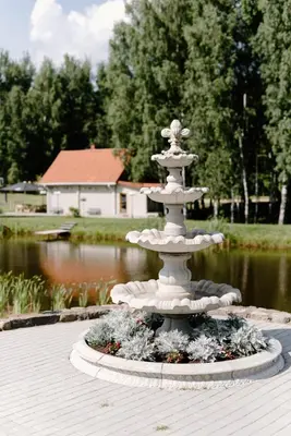 a white fountain in front of a pond at Green Town in Vievis
