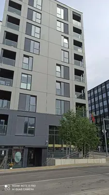 a tall gray building with a tree in front of it at Urban center apartment in Vilnius