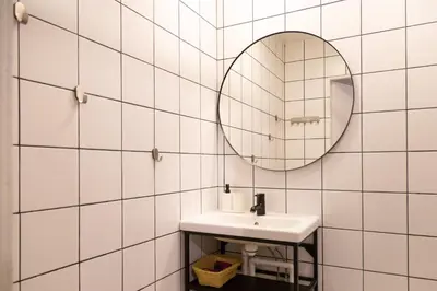 a white tiled bathroom with a sink and a mirror at Visaginas Flat White in Visaginas