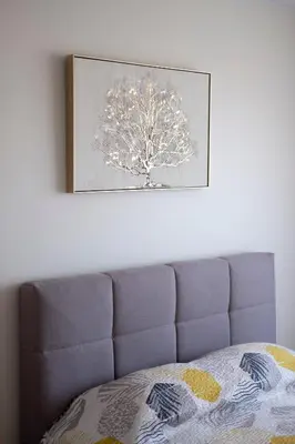 a picture of a tree on the wall above a bed at Amazing Snow Apartments in Druskininkai