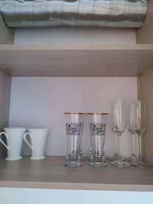 a shelf with wine glasses and cups on it at Upės apartamentai in Biržai