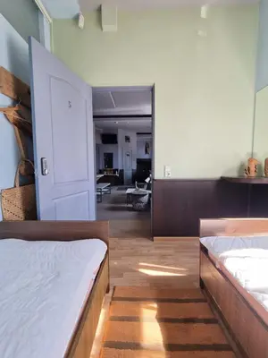a bedroom with two beds and a living room at HelloVilniusHostel in Vilnius