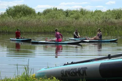 a group of people sitting on kayaks on the water at Wakepond atostogų slėnis in Anykščiai