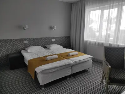 a hotel room with two beds and a chair at B&B Panevėžys in Panevėžys