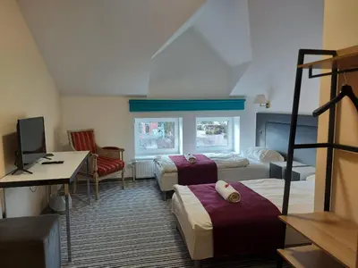 a hotel room with two beds and a desk at B&B Panevėžys in Panevėžys