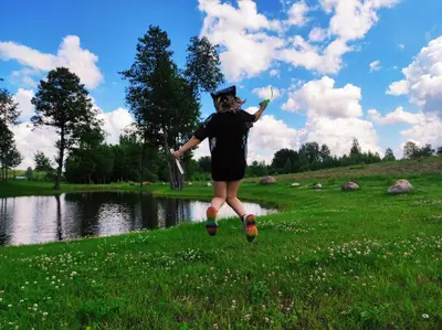 a woman is walking in the grass near a lake at Poilsio namas Vydautiškių slėnis in Sudervė