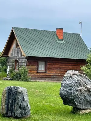 a log house with two large rocks in front of it at Gintaro pirtelė in Lazdijai