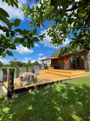 a large wooden deck with a log cabin at Gintaro pirtelė in Lazdijai