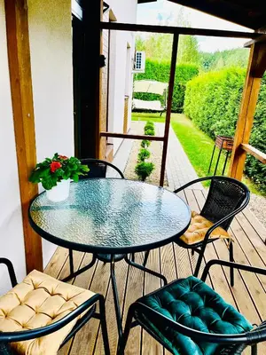 a glass table and chairs on a wooden deck at Royal Resident in Druskininkai