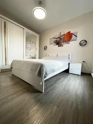 a bedroom with a large white bed and wooden floors at Royal Resident in Druskininkai
