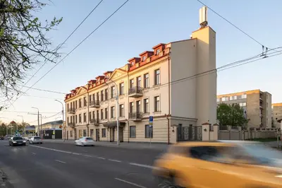 a yellow car driving past a building on a street at CALVARY Hotel & Restaurant Vilnius in Vilnius