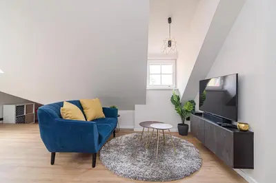 a living room with a blue chair and a tv at Zydu str two bedrooms Apartment by URBAN RENT in Vilnius