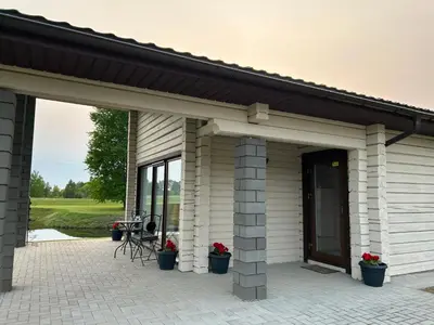 a white house with a black roof and a patio at Lazariškio apartamentai in Martyniškėnai