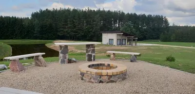 a fire pit in a park with two benches at Lazariškio apartamentai in Martyniškėnai