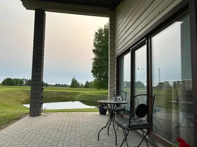 a patio with a table and chairs next to a window at Lazariškio apartamentai in Martyniškėnai