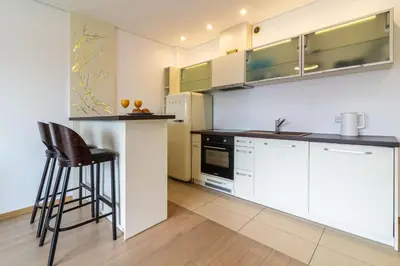 a kitchen with white cabinets and a bar stool at Sunny Center Apt, Covered Parking, Balcony & Self Check-in in Kaunas