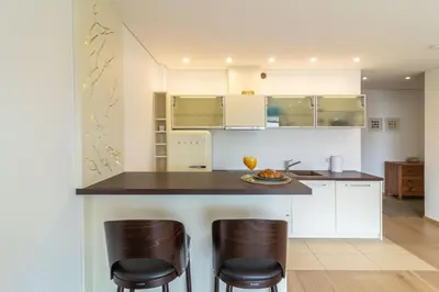 a kitchen with white cabinets and bar stools at Sunny Center Apt, Covered Parking, Balcony & Self Check-in in Kaunas