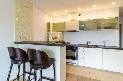a kitchen with white cabinets and black bar stools at Sunny Center Apt, Covered Parking, Balcony & Self Check-in in Kaunas