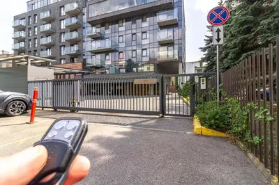 a person holding a remote control in front of a fence at Sunny Center Apt, Covered Parking, Balcony & Self Check-in in Kaunas