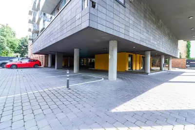 a building with a red car parked in a parking lot at Sunny Center Apt, Covered Parking, Balcony & Self Check-in in Kaunas