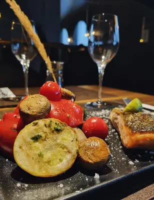a plate of food with vegetables and wine glasses at Brut Wine Hotel in Zarasai