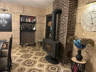 a living room with a fireplace and a clock on the wall at Forest house for family in Lebeniškiai