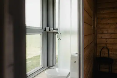 a bathroom with a toilet and a window at Vienkiemio oazė - Skandinaviškas namelis su vaizdu į tvenkinį in Galvokai