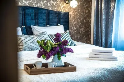 a tray with purple flowers and two cups on a bed at LYRA63 Large 80sq m TOP 14 floor in Šiauliai