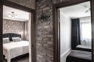 a bedroom with a brick wall with a bed and a mirror at LYRA63 Large 80sq m TOP 14 floor in Šiauliai