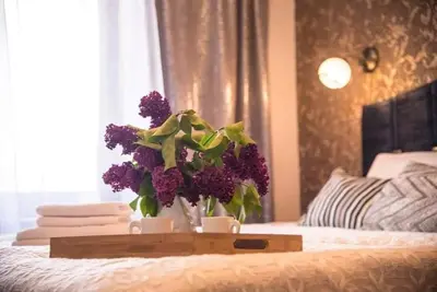 a tray with a bouquet of purple flowers on a bed at LYRA63 Large 80sq m TOP 14 floor in Šiauliai