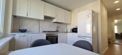 a kitchen with white cabinets and a table and chairs at Sonata apartment in Panevėžys