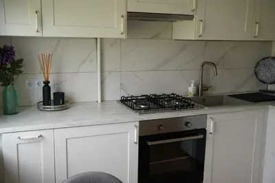 a kitchen with white cabinets and a stove top oven at Sonata apartment in Panevėžys