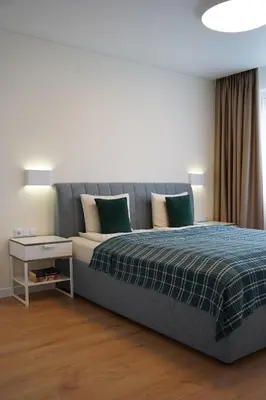 a bedroom with a bed with a blue blanket at Sonata apartment in Panevėžys