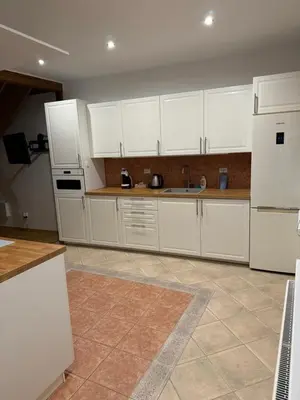 a large kitchen with white cabinets and appliances at Laurentroom Townhouse in Ukmergė