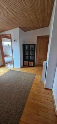 a living room with a wooden ceiling and a rug at Laurentroom Townhouse in Ukmergė
