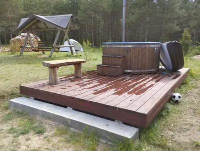 a wooden deck with a hot tub and a bench at Piglet house in Alytus