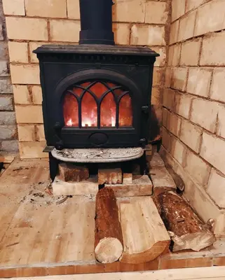 a black stove with a brick wall and a log at Piglet house in Alytus