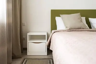 a bedroom with a bed with a white nightstand next to it at 1 House Between two lakes in Vilnius