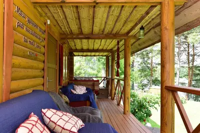 a porch of a log cabin with a blue couch at Sodyba “Rita” in Mėčiūnai