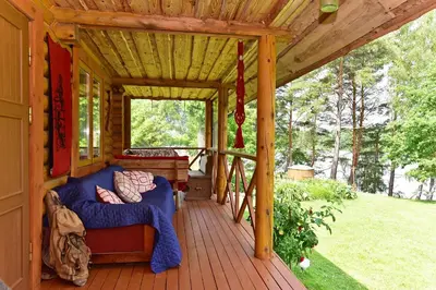 a porch of a cabin with a couch on a deck at Sodyba “Rita” in Mėčiūnai
