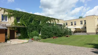 an ivy covered building with a lawn in front of it at Berzu aleja in Birštonas