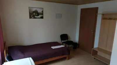 a small bedroom with a bed and a chair at Berzu aleja in Birštonas