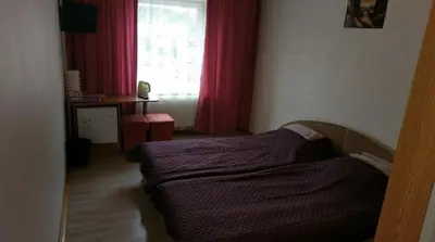 a bedroom with a bed and a window with red curtains at Berzu aleja in Birštonas