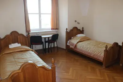 a bedroom with two beds and a table with chairs at Liškiavos vienuolyno ansamblis in Liškiava