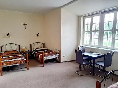 a bedroom with two beds and a table and chairs at Liškiavos vienuolyno ansamblis in Liškiava