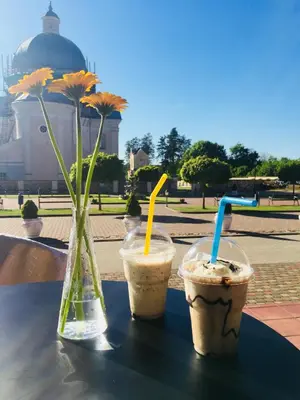 two drinks on a table with a vase with flowers at Liškiavos vienuolyno ansamblis in Liškiava