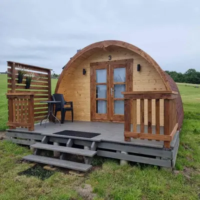 a large wooden cabin in a field with a table and bench at Camp Genys in Jurbarkas